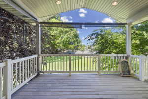 Covered outdoor patio featuring wood-finish decking, white balusters, and recessed ceiling lighting