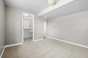 Carpeted room featuring a built-in closet with shelving, neutral wall paint, white trim, and a ceiling-mounted light fixture