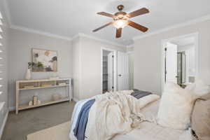 Carpeted bedroom featuring crown molding and a ceiling fan with integrated lighting