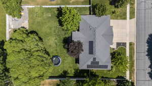 Gable roofline residence featuring solar panels, a concrete driveway, and established landscaping