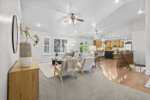 Open-concept living space featuring vaulted ceilings, recessed lighting, a ceiling fan, and plantation shutters
