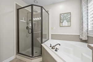 Corner glass-enclosed shower with dark bronze framing and a built-in tub featuring bronze fixtures