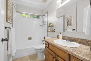 Full bathroom featuring a single vanity with wood cabinetry, a laminate countertop, and a built-in sink