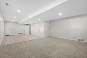 Spacious room featuring recessed ceiling lighting, a partial wood-finish flooring area, and a large carpeted section