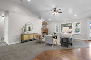 Spacious living area featuring a vaulted ceiling with a ceiling fan, recessed lighting, and white plantation shutters