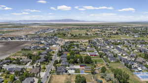 Expansive residential area featuring a variety of architectural styles, mature landscaping, paved roadways, and mountain range backdrop