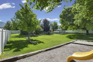 Expansive backyard featuring a manicured lawn, established trees, and white privacy fencing