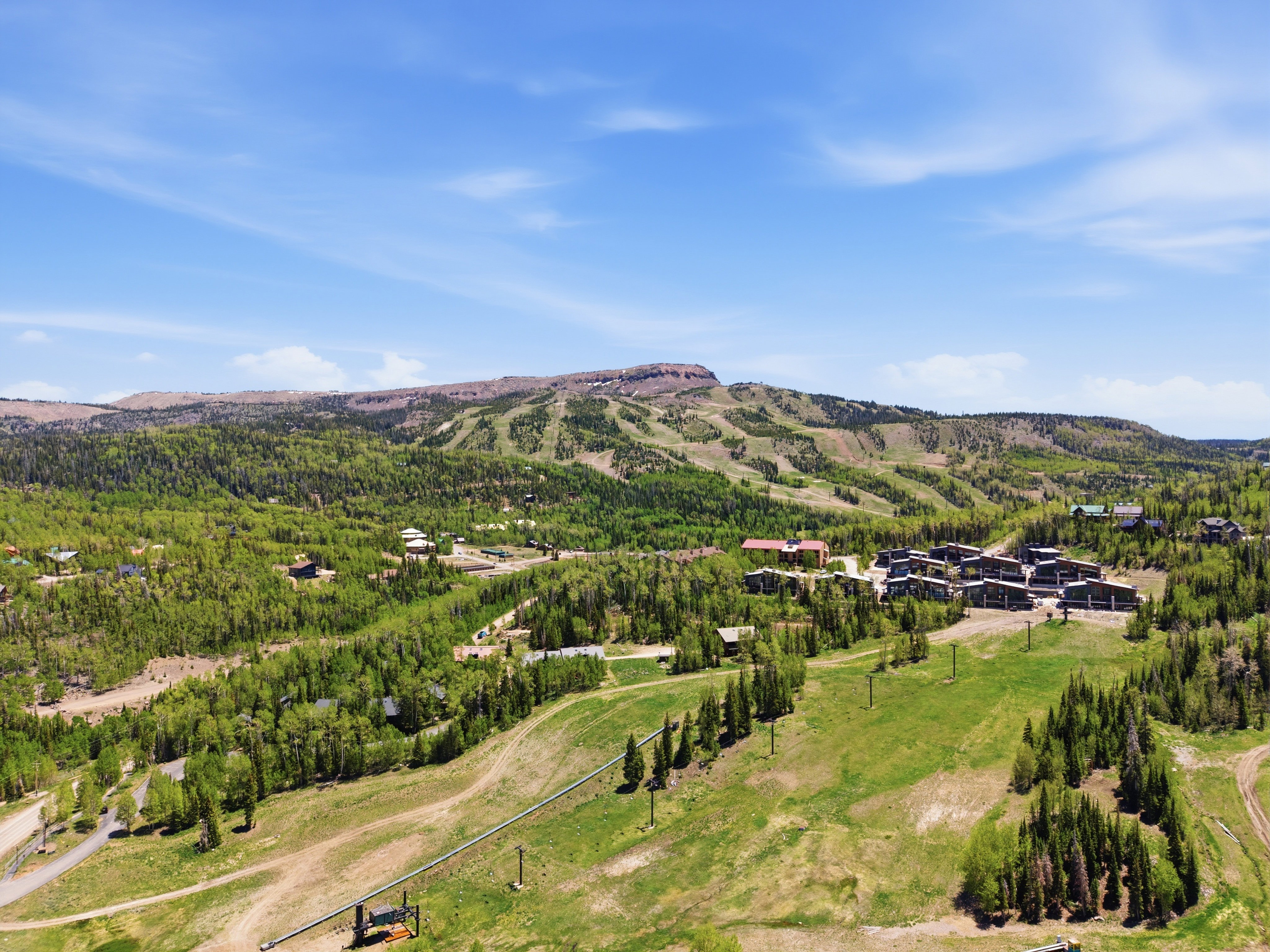 Expansive mountain landscape featuring a ski resort with multiple runs, dense evergreen forests, scattered residential properties, and a prominent mountain backdrop