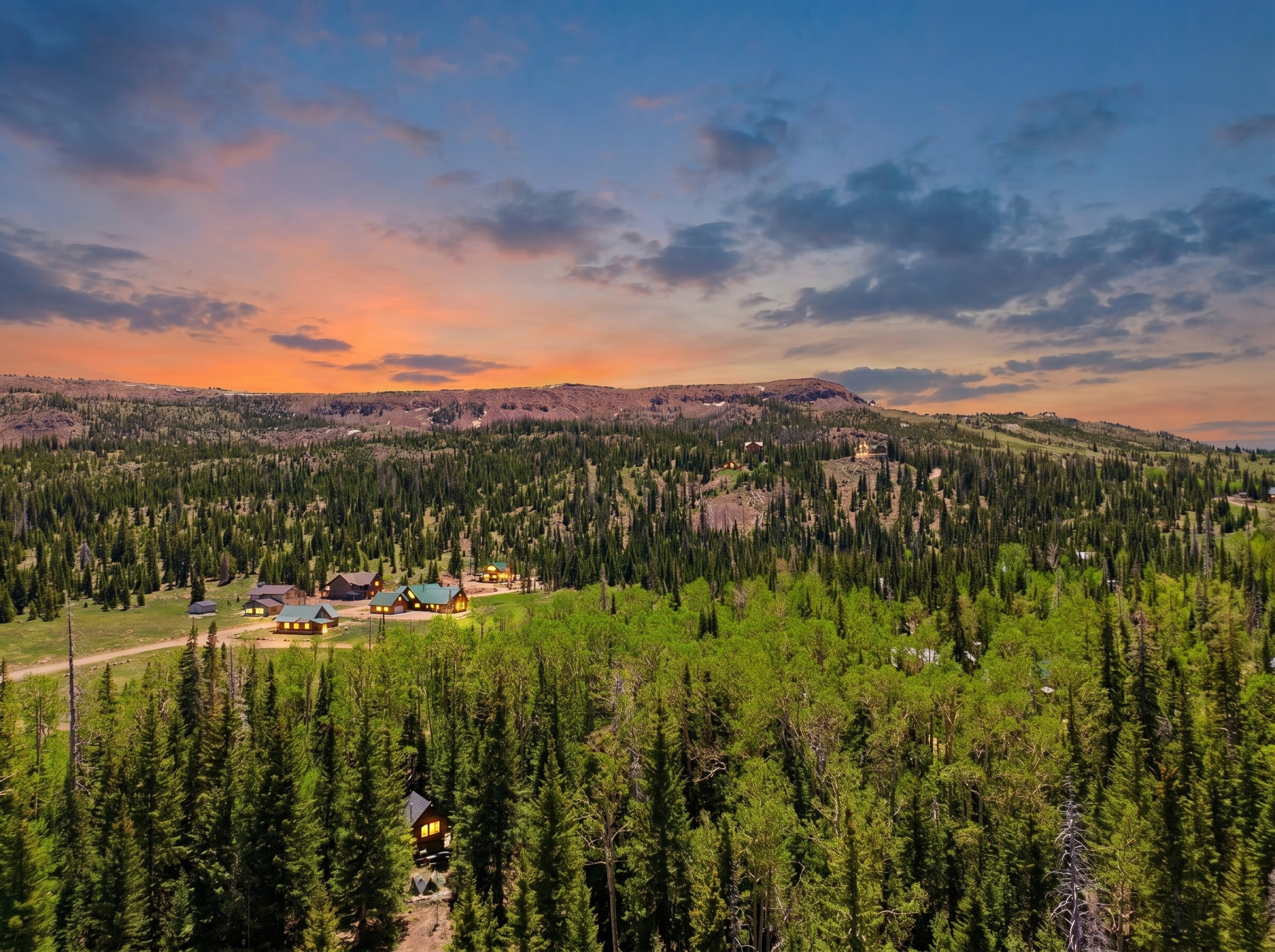 Expansive mountain property featuring a collection of multiple cabin-style residences set amidst dense evergreen and deciduous trees