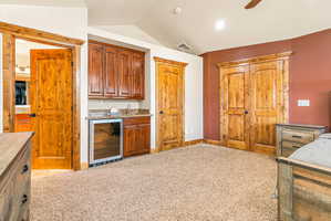 Wet bar featuring wood cabinetry, undermount sink, and beverage refrigerator
