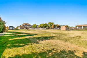 Expansive grassy area featuring a detached storage shed
