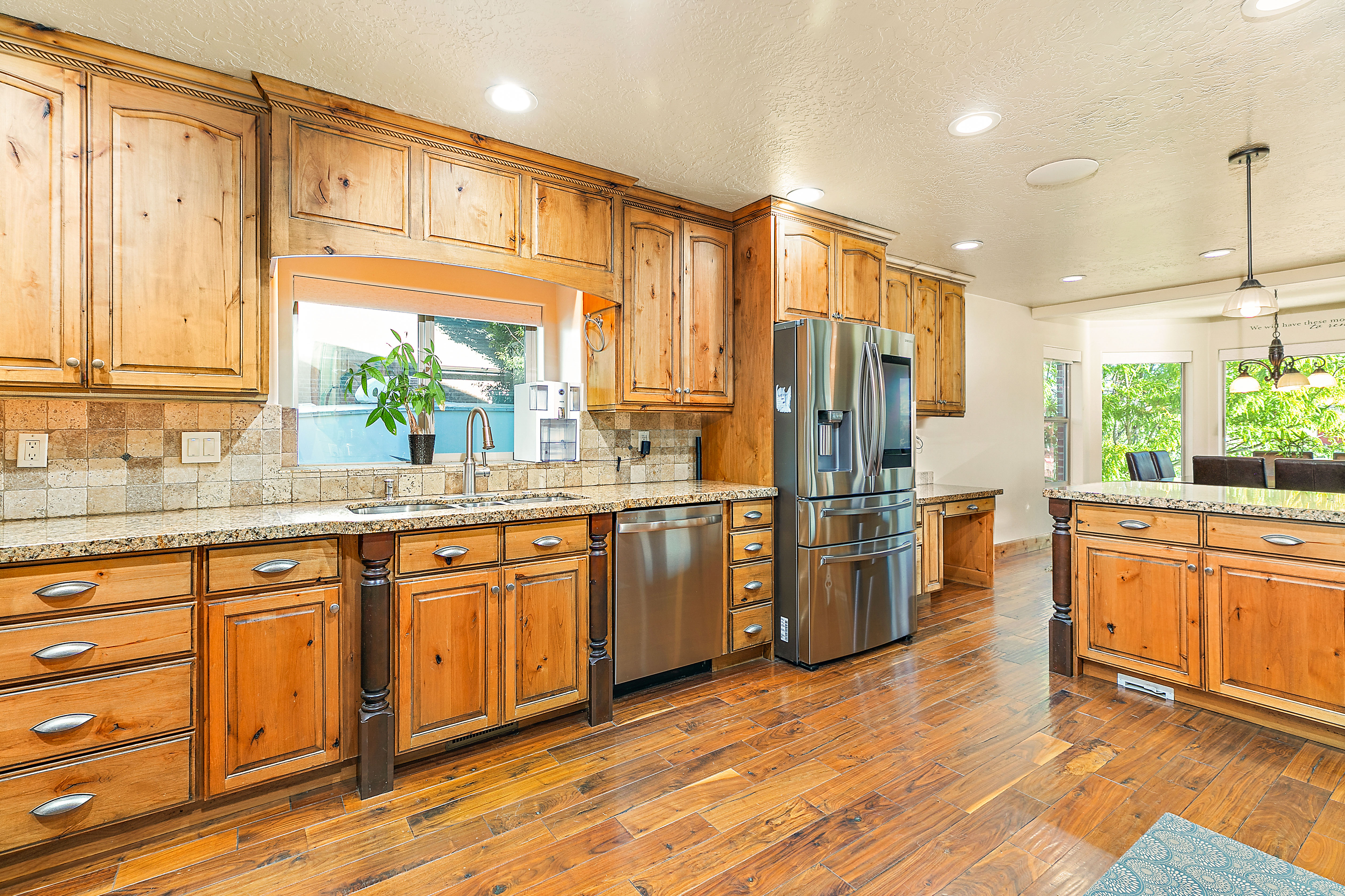 Kitchen featuring wood-finish cabinetry, granite countertops, and stainless steel appliances including a refrigerator and dishwasher