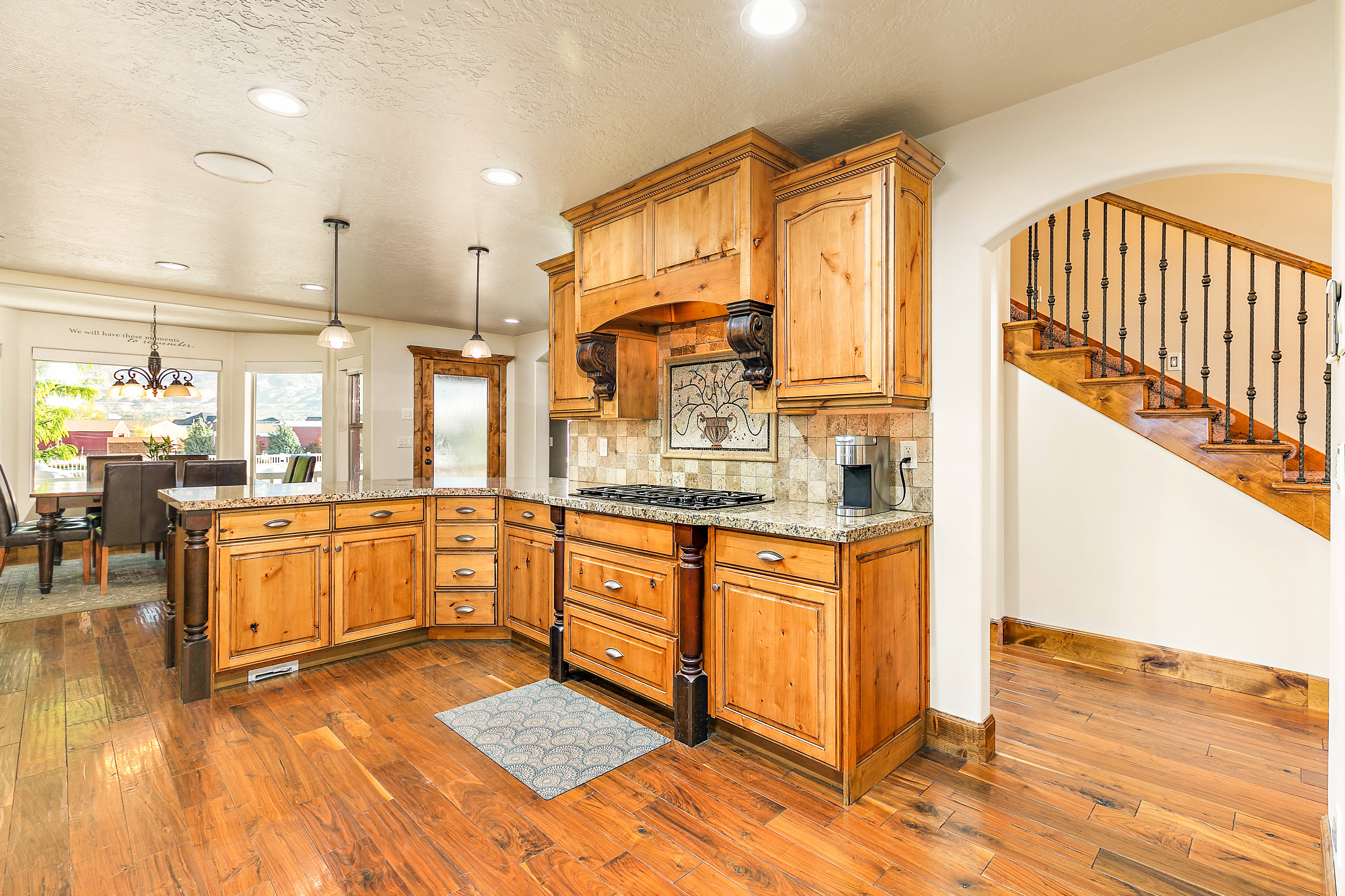 Spacious kitchen featuring natural wood cabinetry, granite countertops, and wood-finish flooring