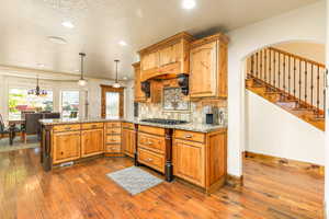 Spacious kitchen featuring natural wood cabinetry, granite countertops, and wood-finish flooring
