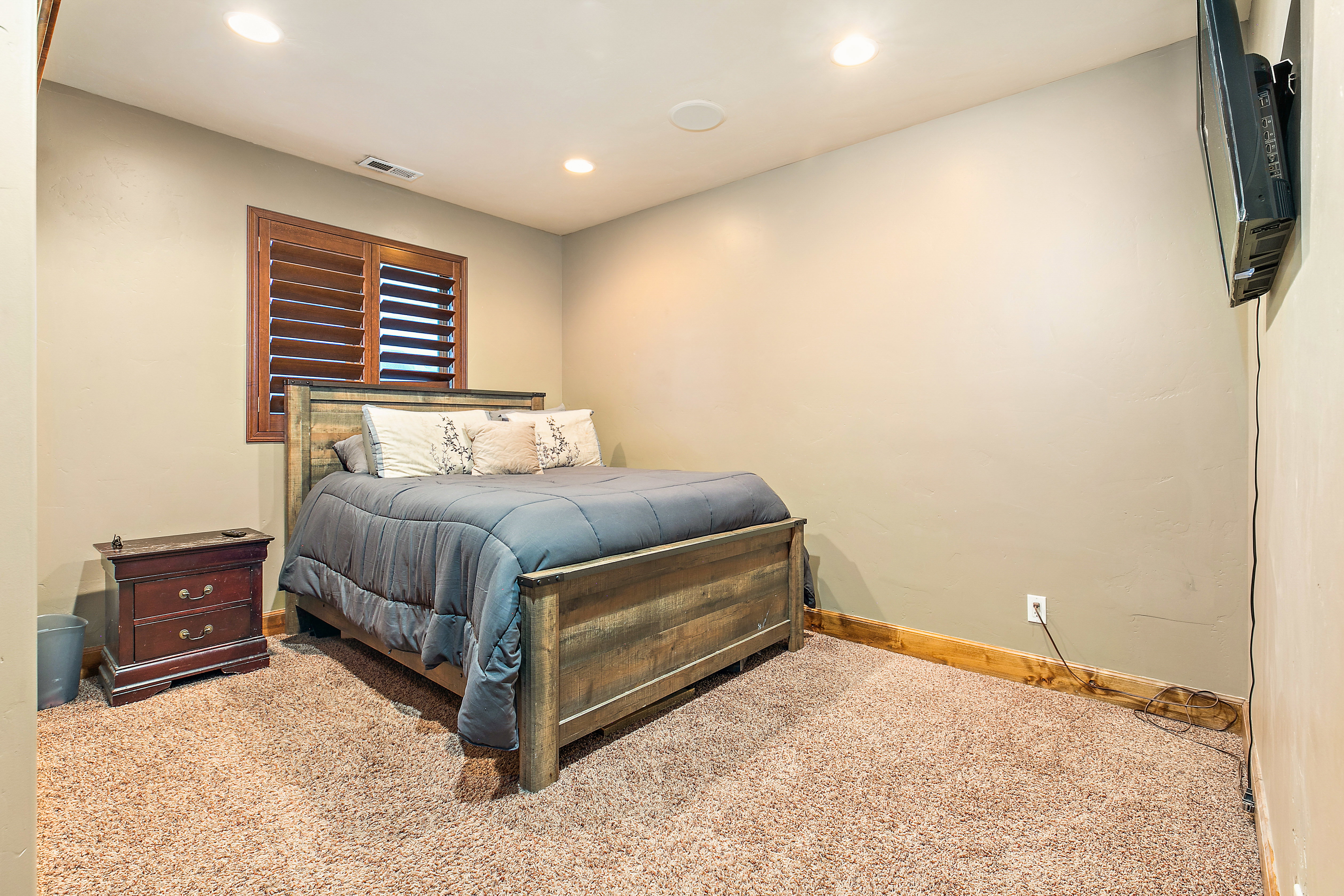 Plush carpeted room featuring a window with wood plantation shutters