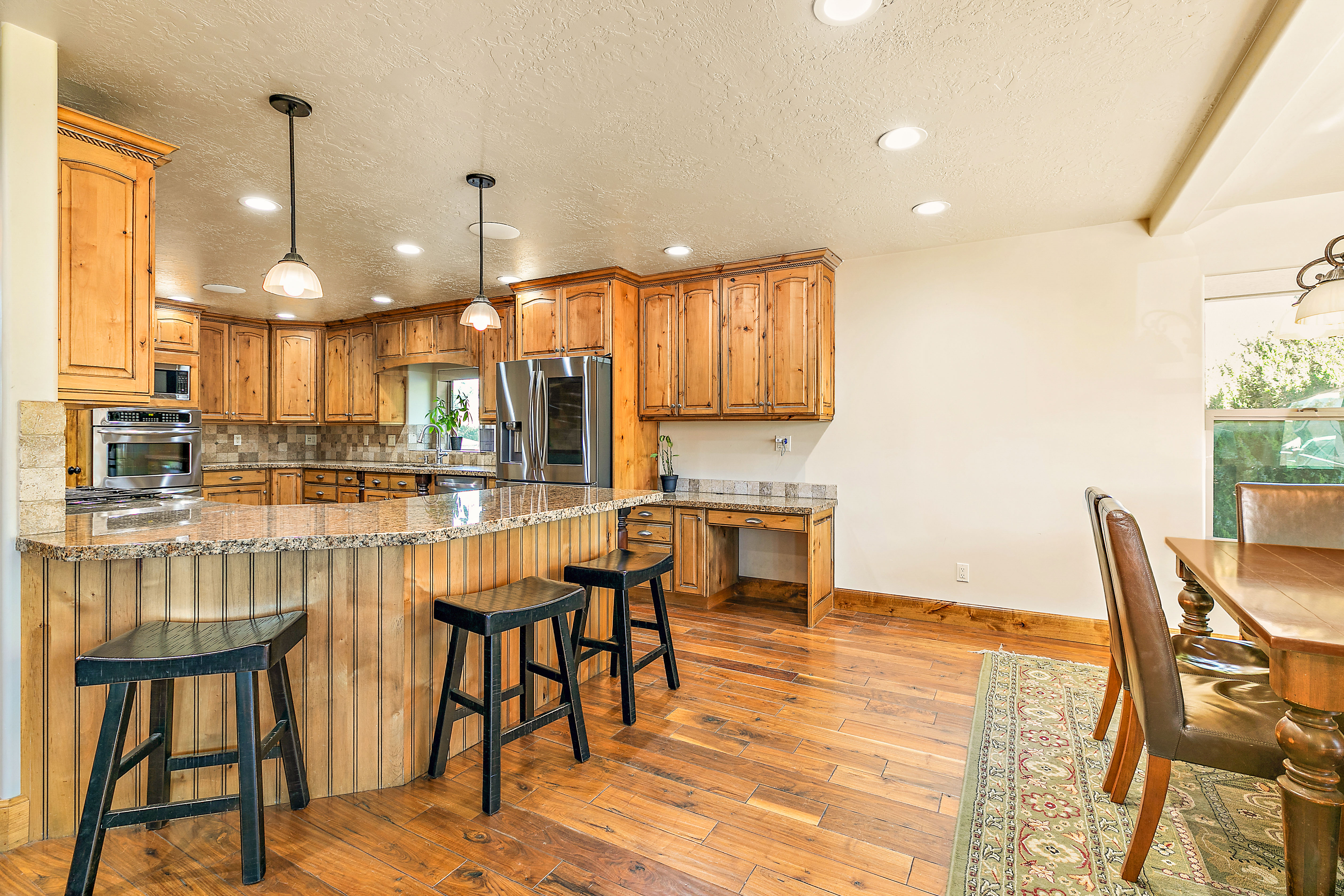 Kitchen featuring wood-finish cabinetry, stainless steel appliances, granite countertops, and a stone tile backsplash