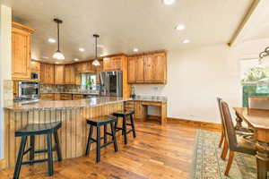 Kitchen featuring wood-finish cabinetry, stainless steel appliances, granite countertops, and a stone tile backsplash