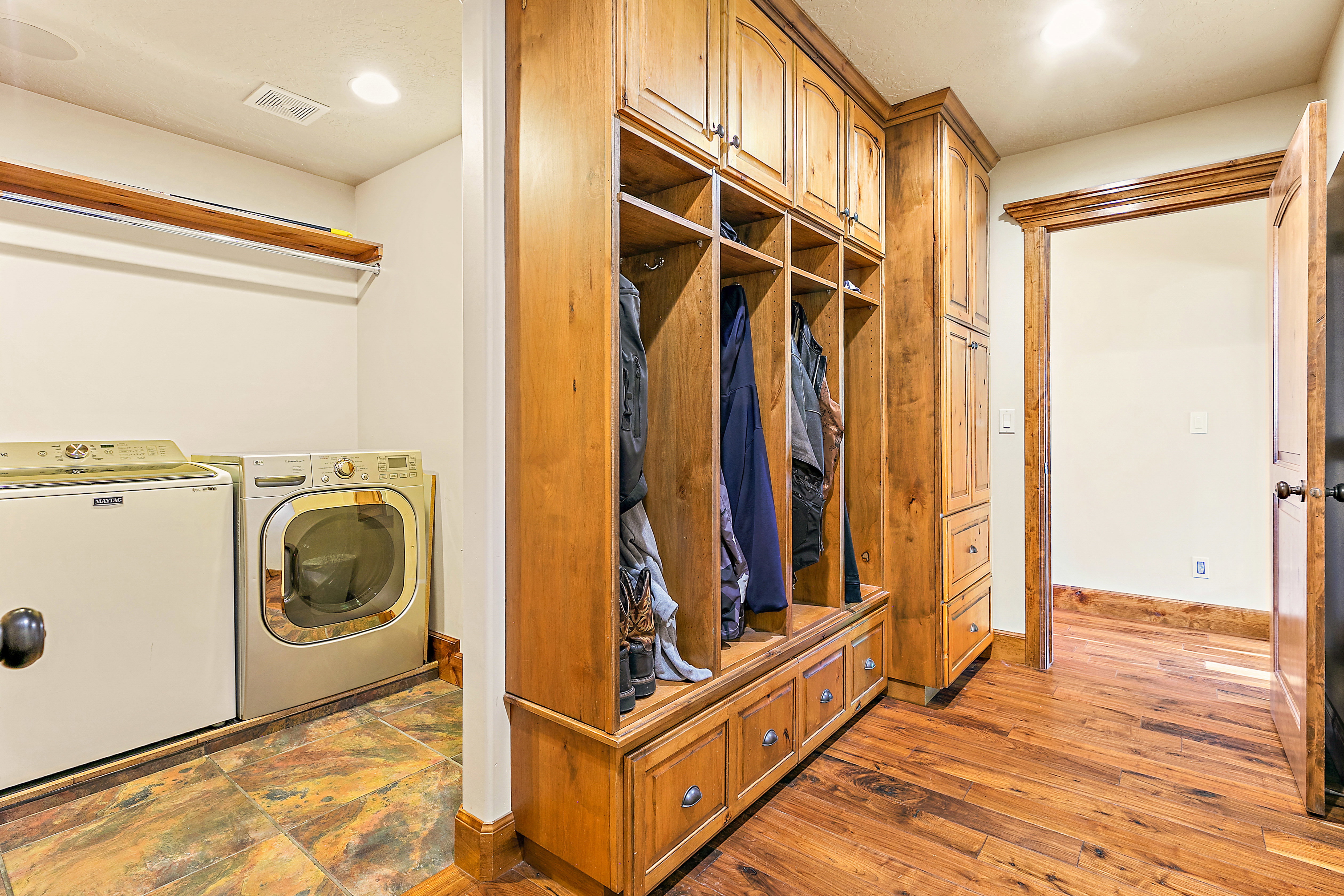 Dedicated laundry area featuring a tile floor and built-in wood-finish cabinetry