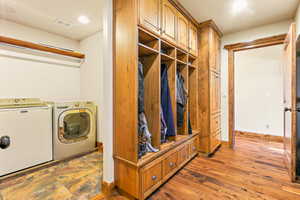 Dedicated laundry area featuring a tile floor and built-in wood-finish cabinetry