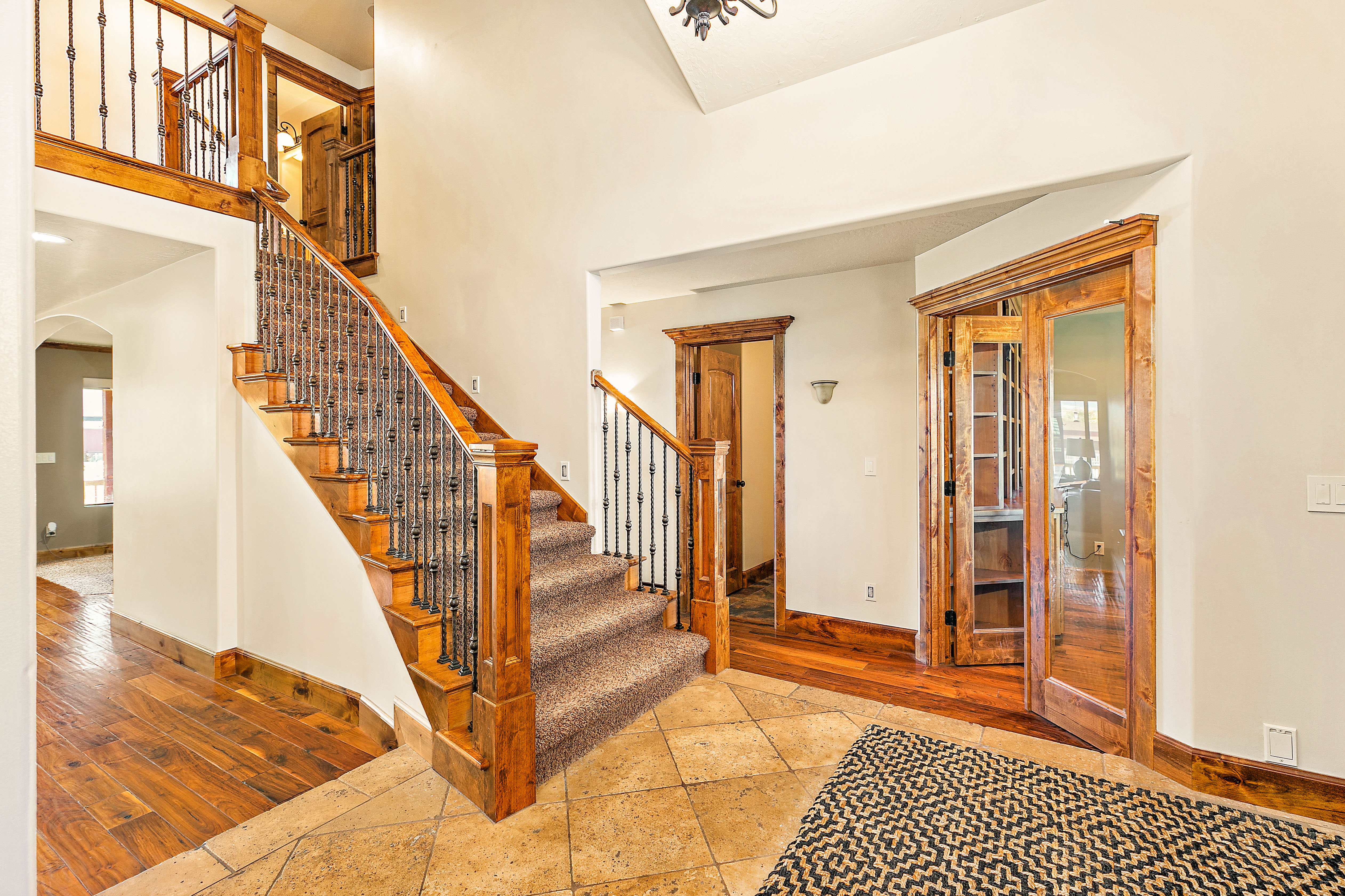Grand entryway featuring a staircase with wood treads, carpeted steps, and wrought iron balusters