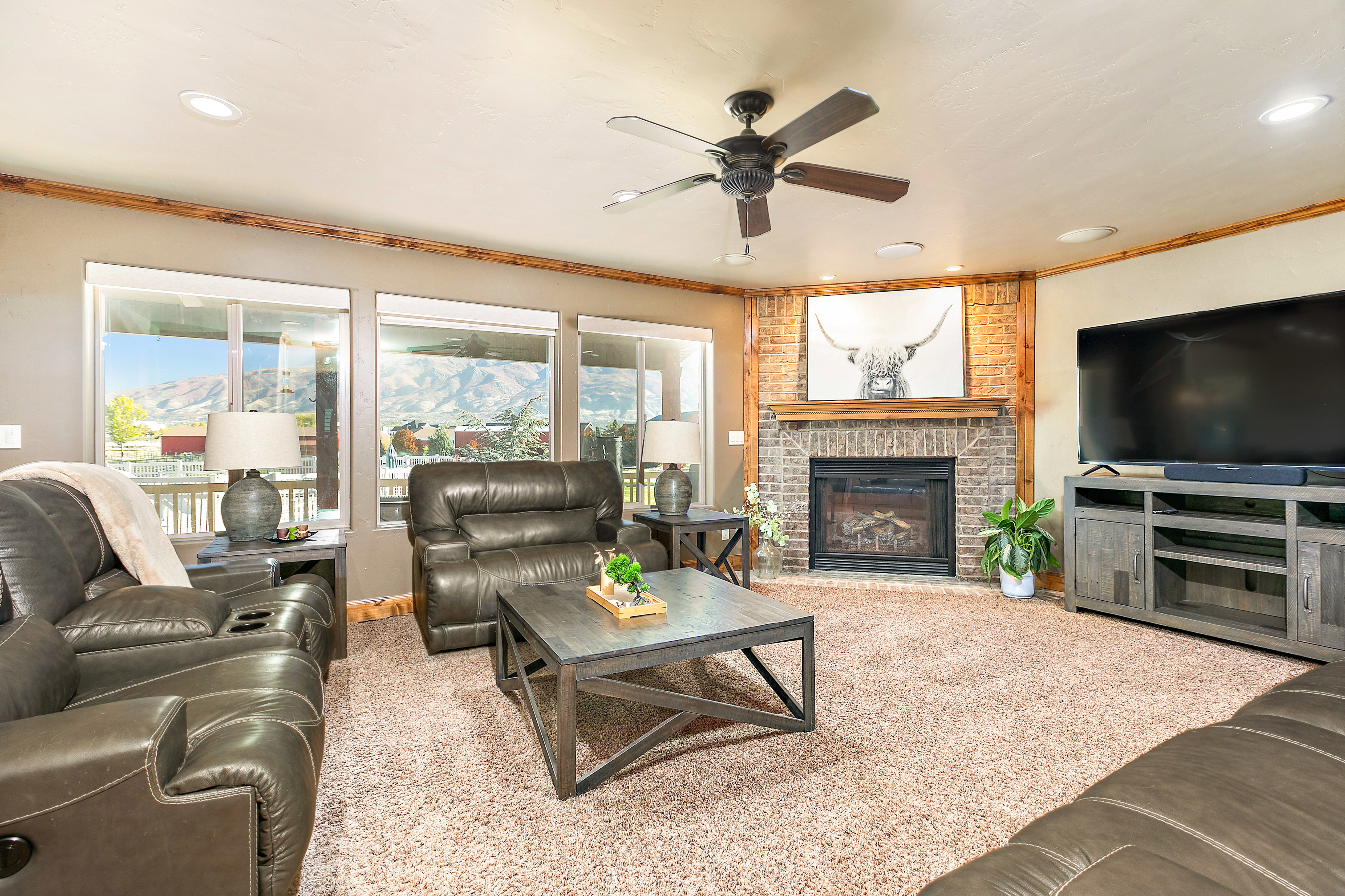 Living area featuring a brick fireplace with wood mantel, wood-finish accent wall, and multiple windows