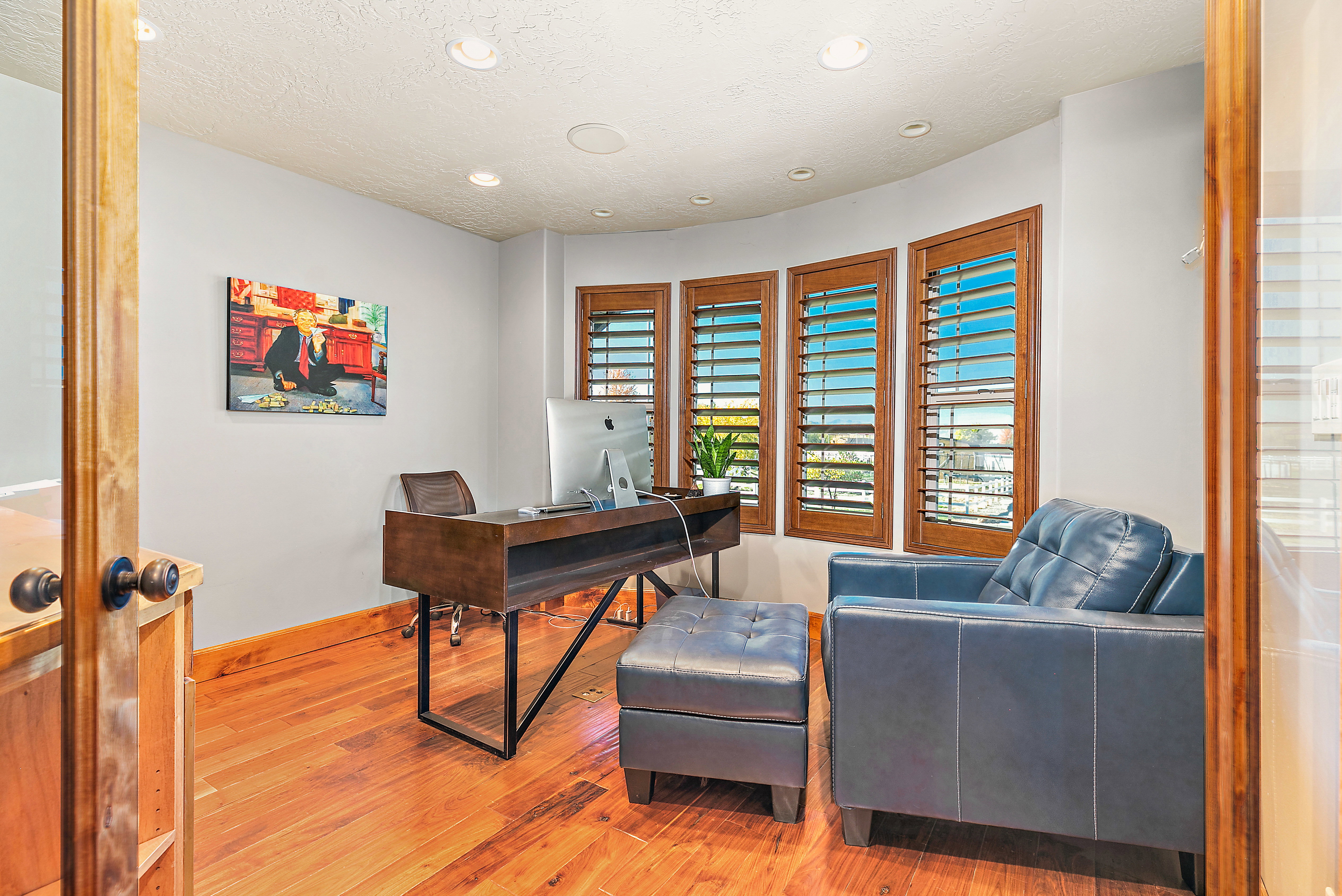 Spacious room featuring wood-finish flooring, recessed lighting, and a curved wall with three windows