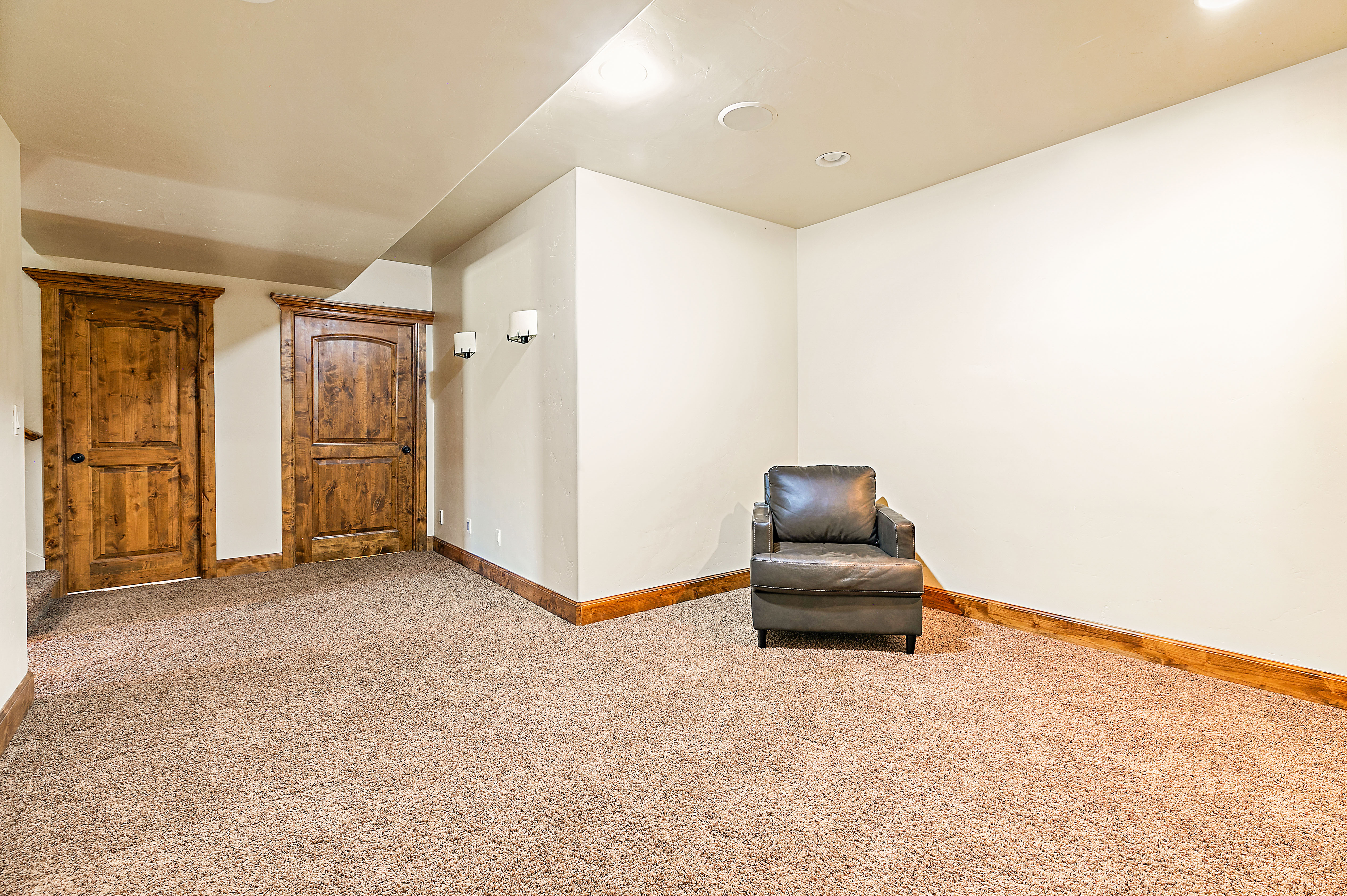 Carpeted room featuring recessed lighting, two panel doors with detailed wood trim, and wall-mounted sconces