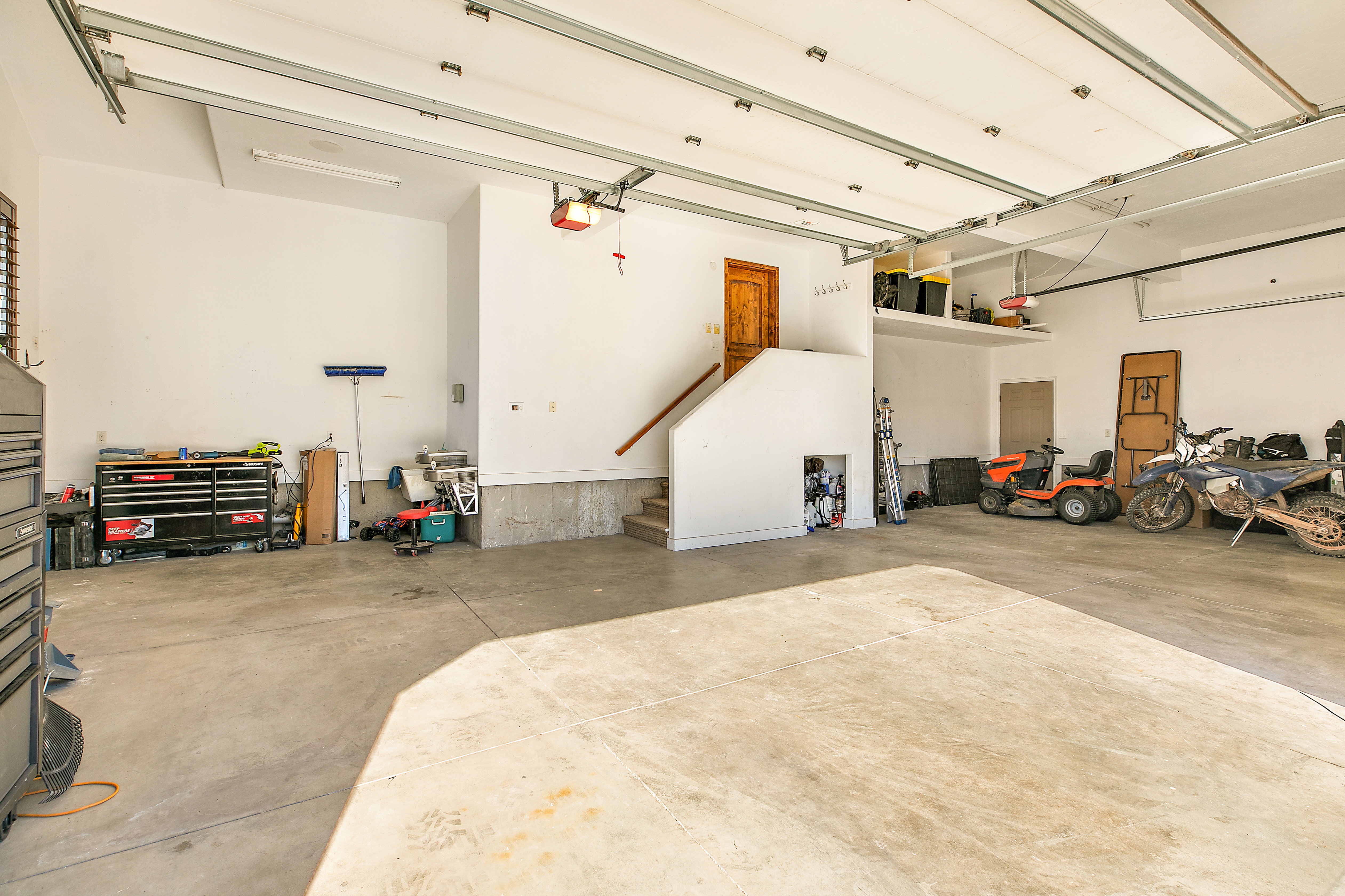 Spacious garage with high ceilings, exposed ceiling beams, and concrete flooring