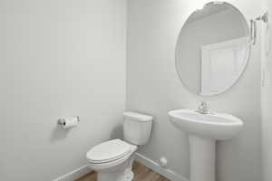 Pedestal sink with chrome faucet, complemented by a large oval mirror