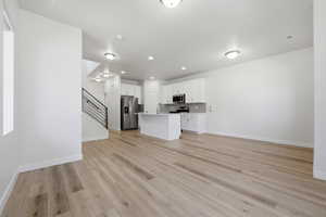 Open-concept living area with wood-finish flooring, white walls, and recessed lighting