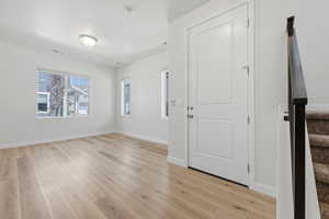 Spacious interior showcasing light wood-finish flooring, multiple windows providing ample natural light, a contemporary flush-mount ceiling light, and a modern white paneled door