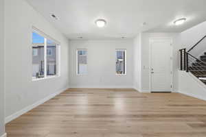 Spacious interior featuring light wood-finish flooring, white walls, and multiple windows