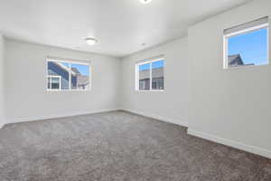 Carpeted room featuring three windows, white walls, white baseboards, and ceiling-mounted flush light fixtures
