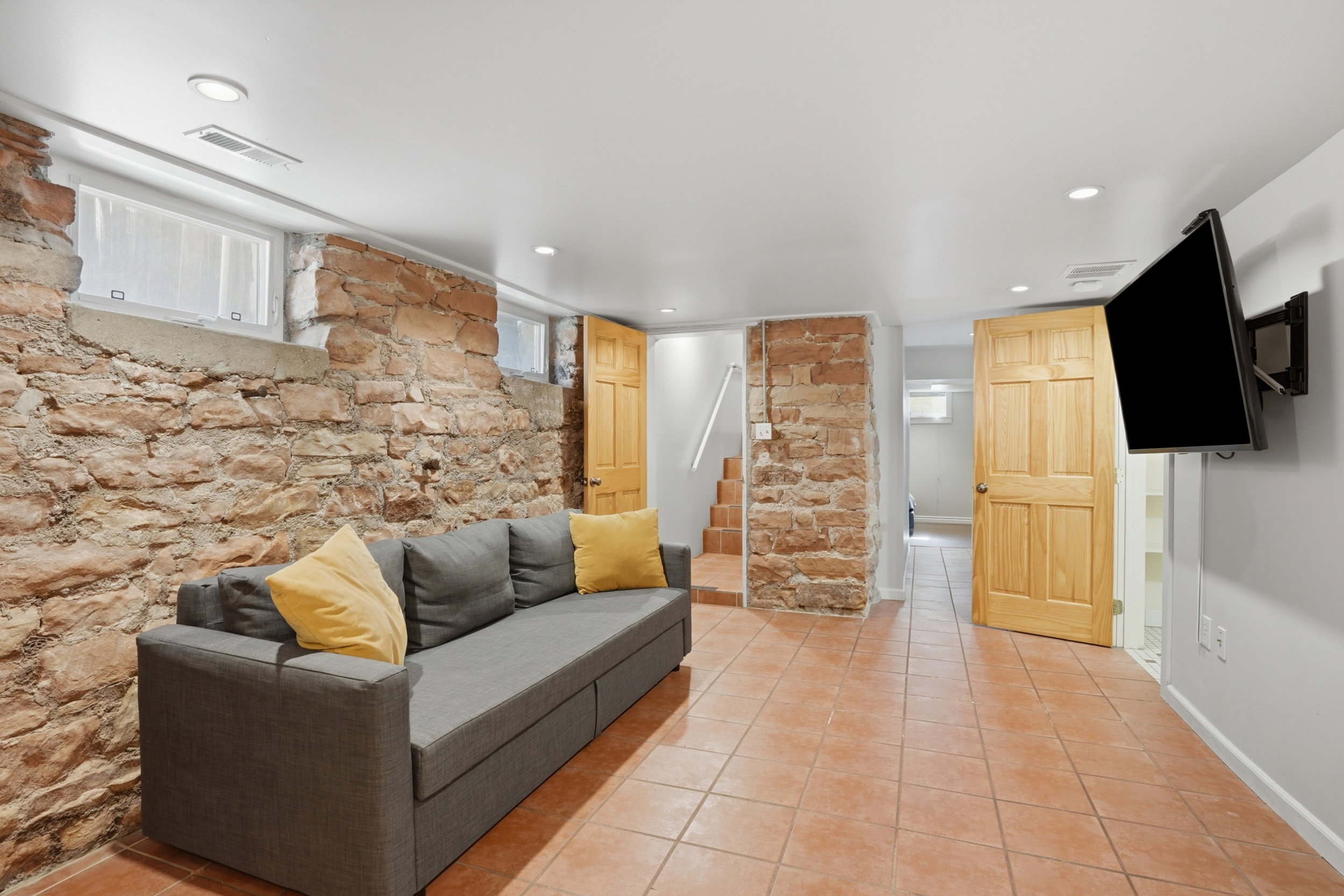 Exposed stone wall detailing, recessed lighting, and tile flooring