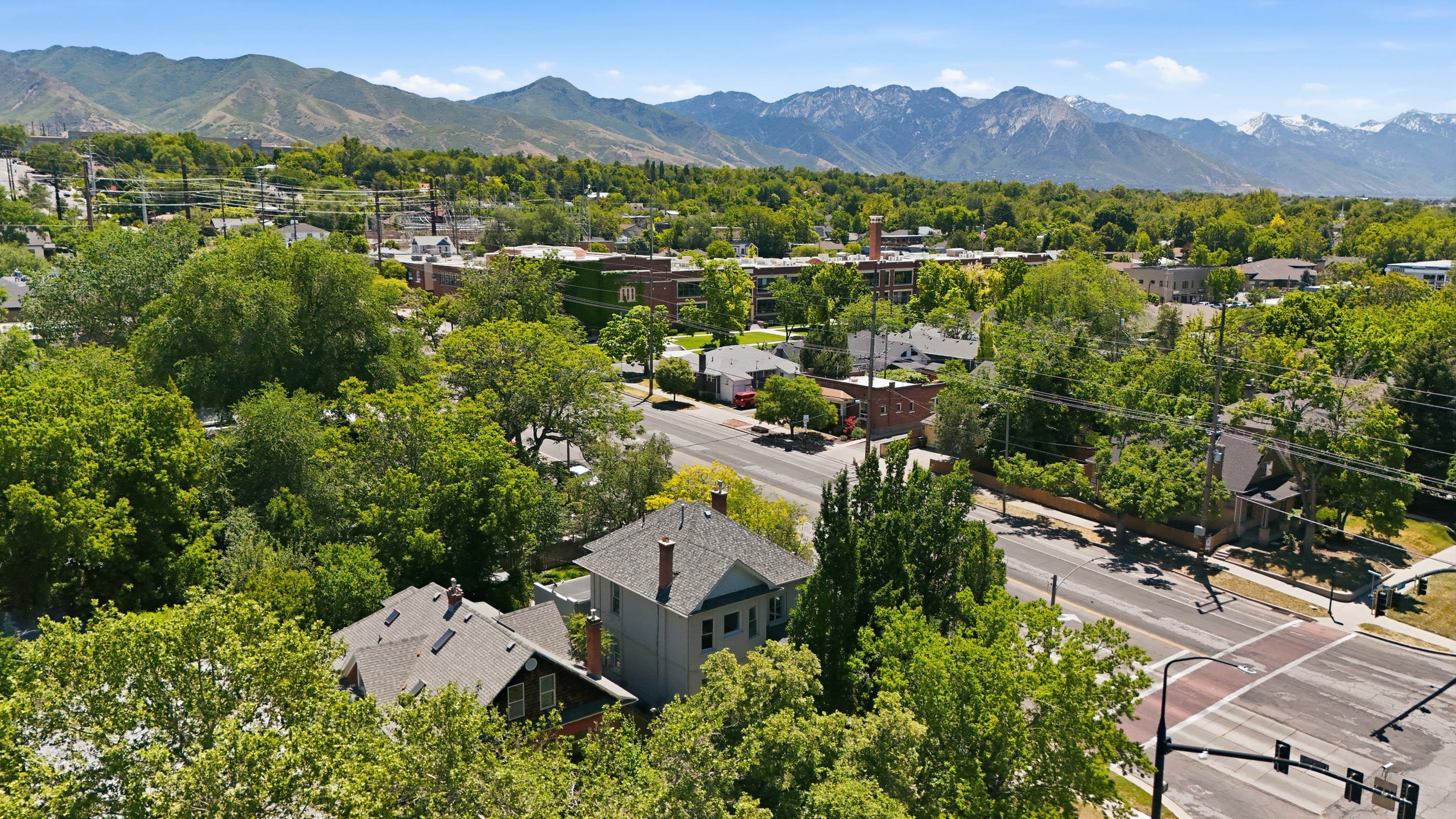 Neighborhood setting featuring mature trees, paved streets, and a mountainous backdrop