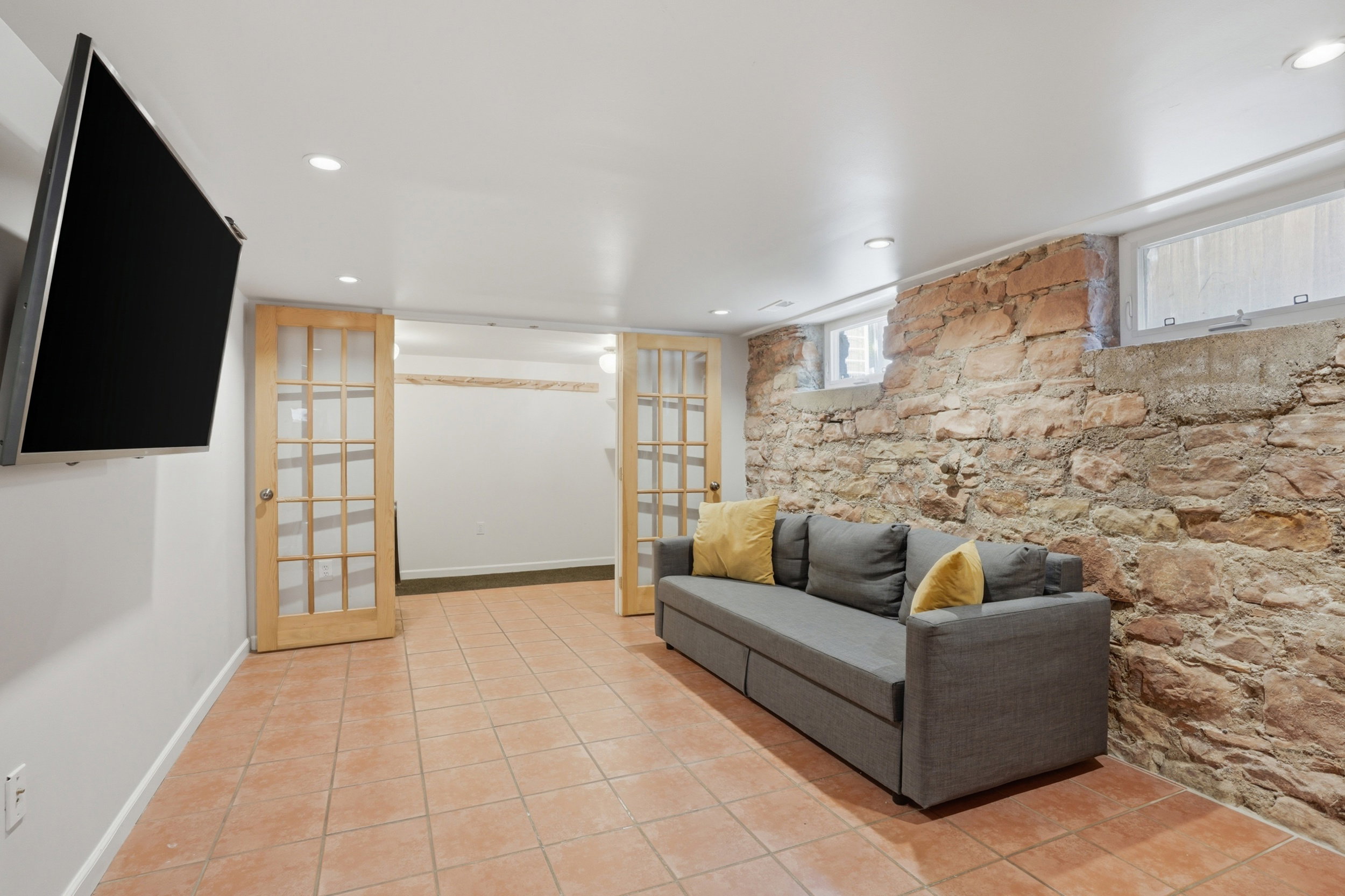 Finished basement space featuring a stone accent wall, recessed lighting, and tile flooring