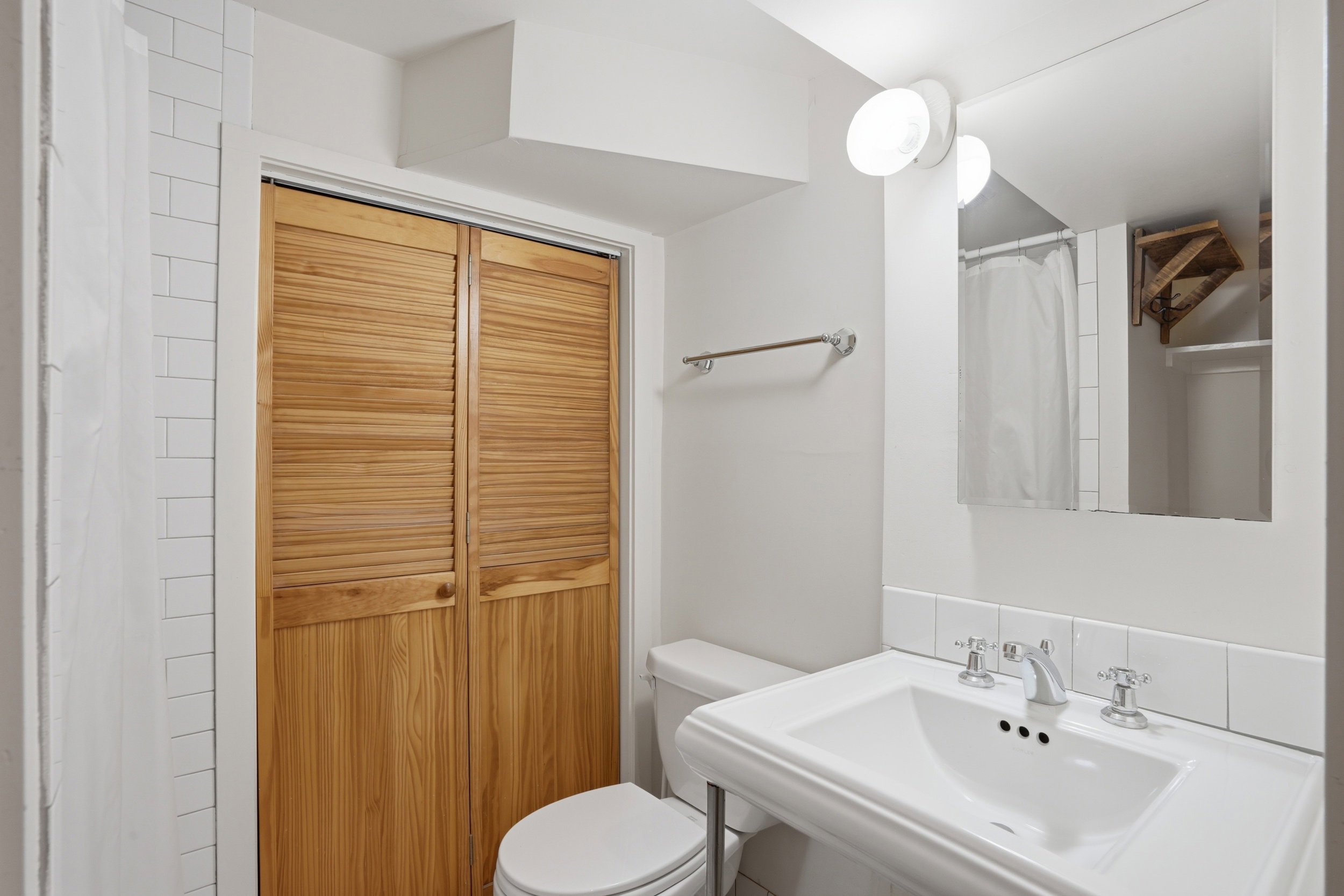 Pedestal sink with chrome fixtures and a vanity mirror