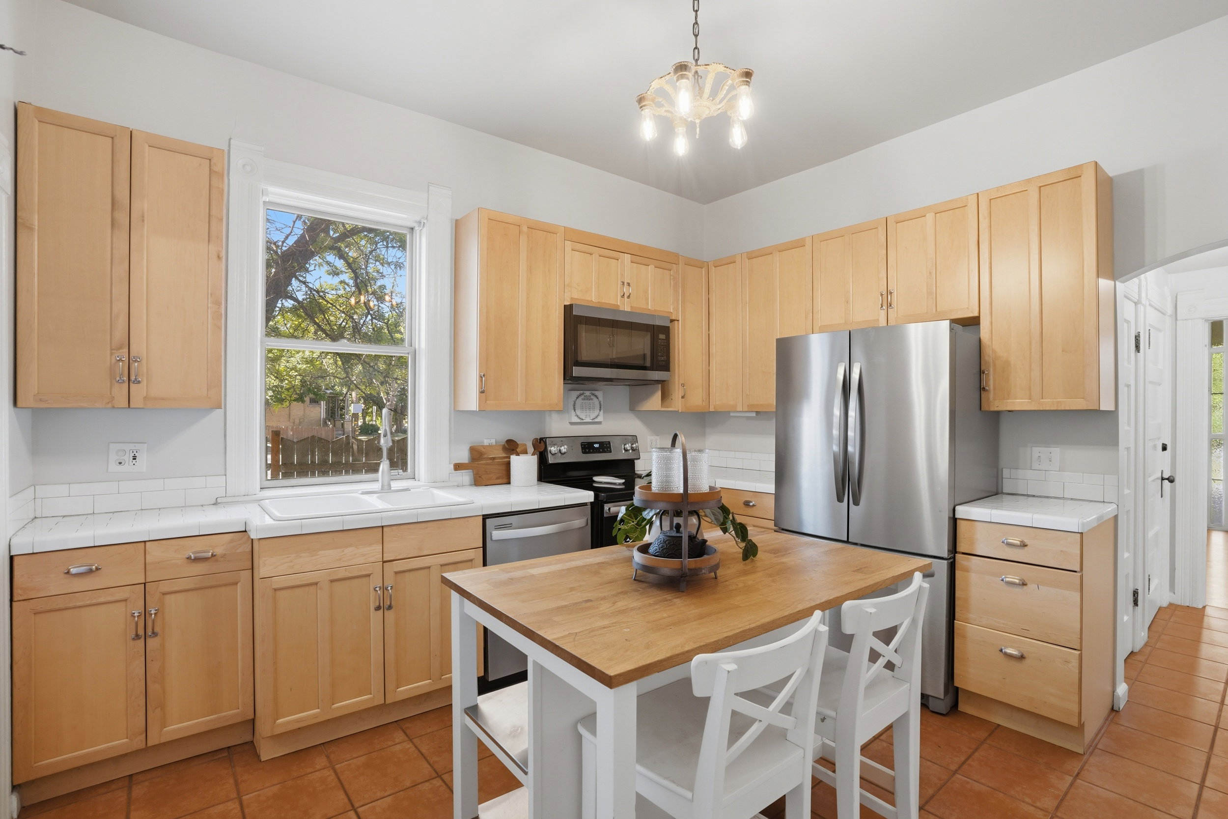 Kitchen featuring light wood cabinetry, white countertops, subway tile backsplash, and stainless steel appliances