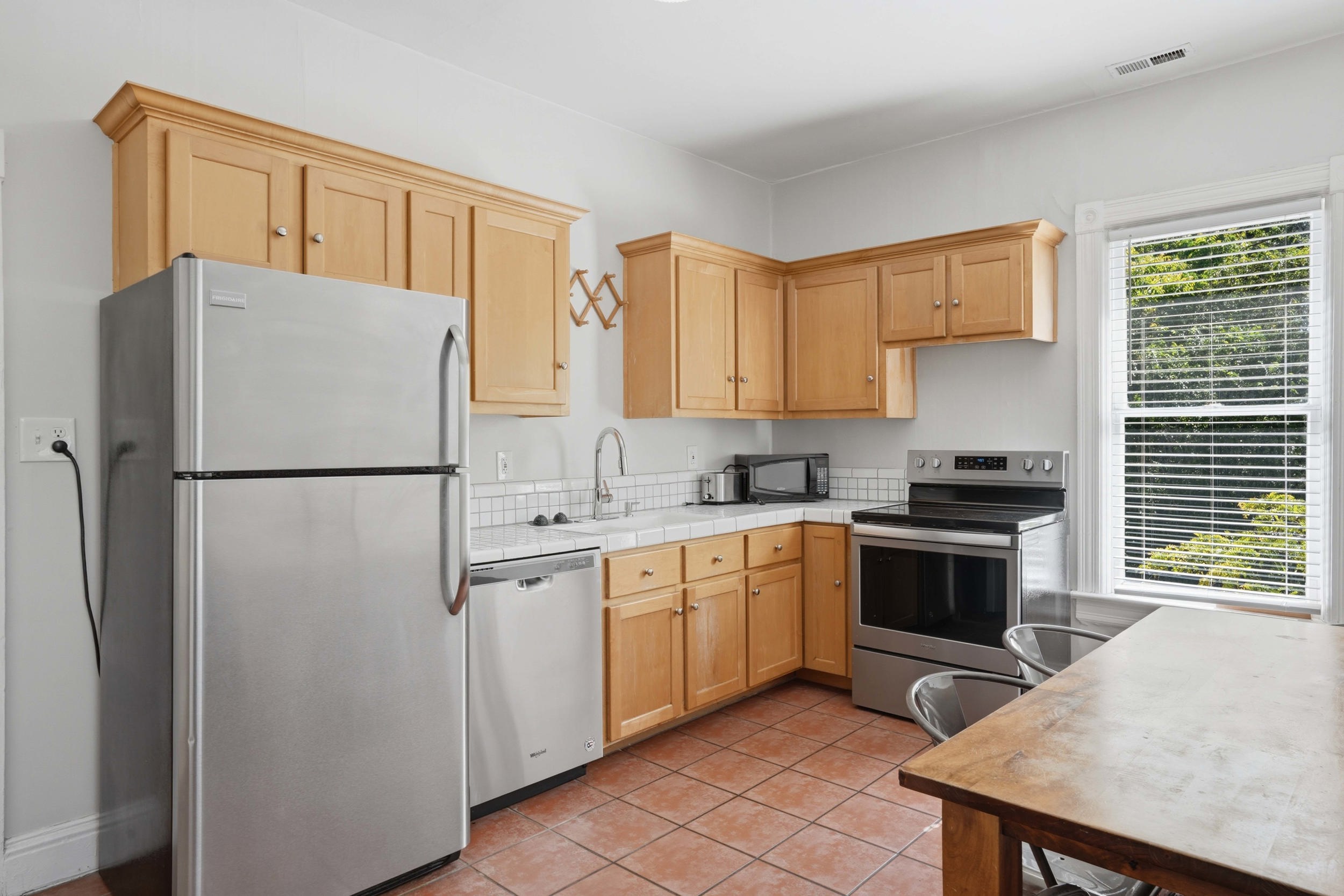 Kitchen featuring light wood cabinetry, white subway tile backsplash, and stainless steel appliances