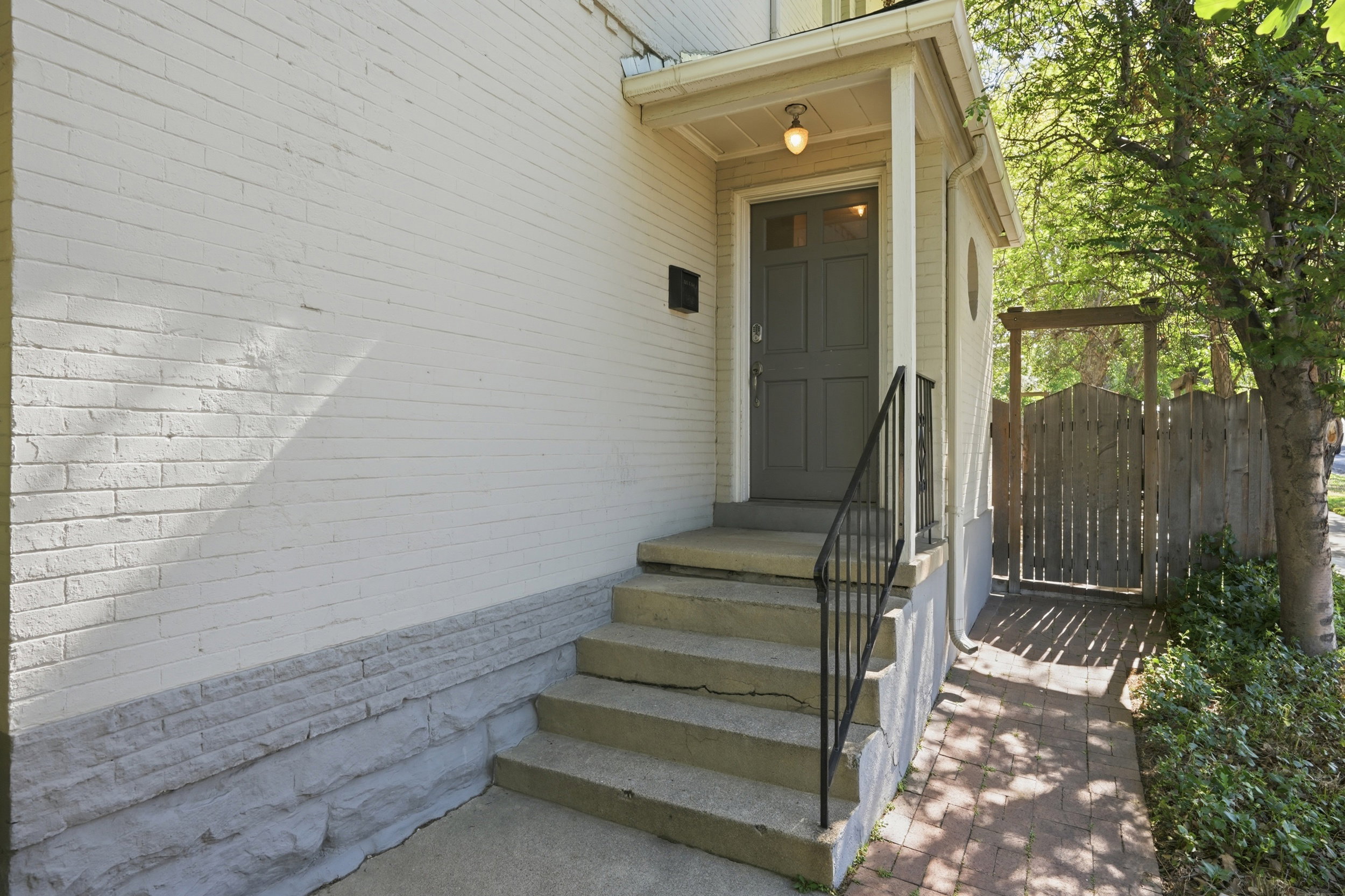 Covered entry with concrete steps and black metal handrail