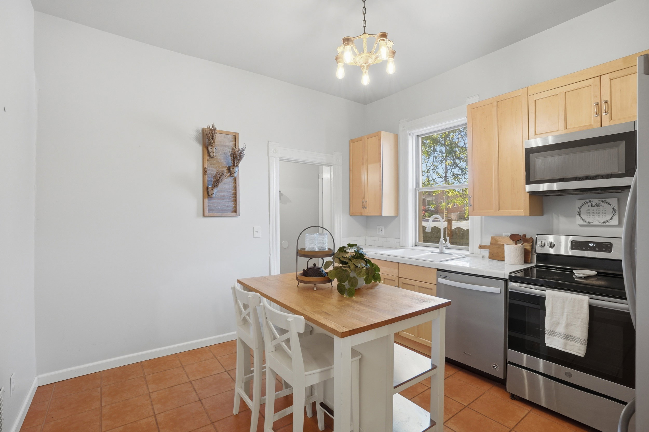Kitchen featuring neutral cabinetry, stainless steel appliances, a white sink, and a window