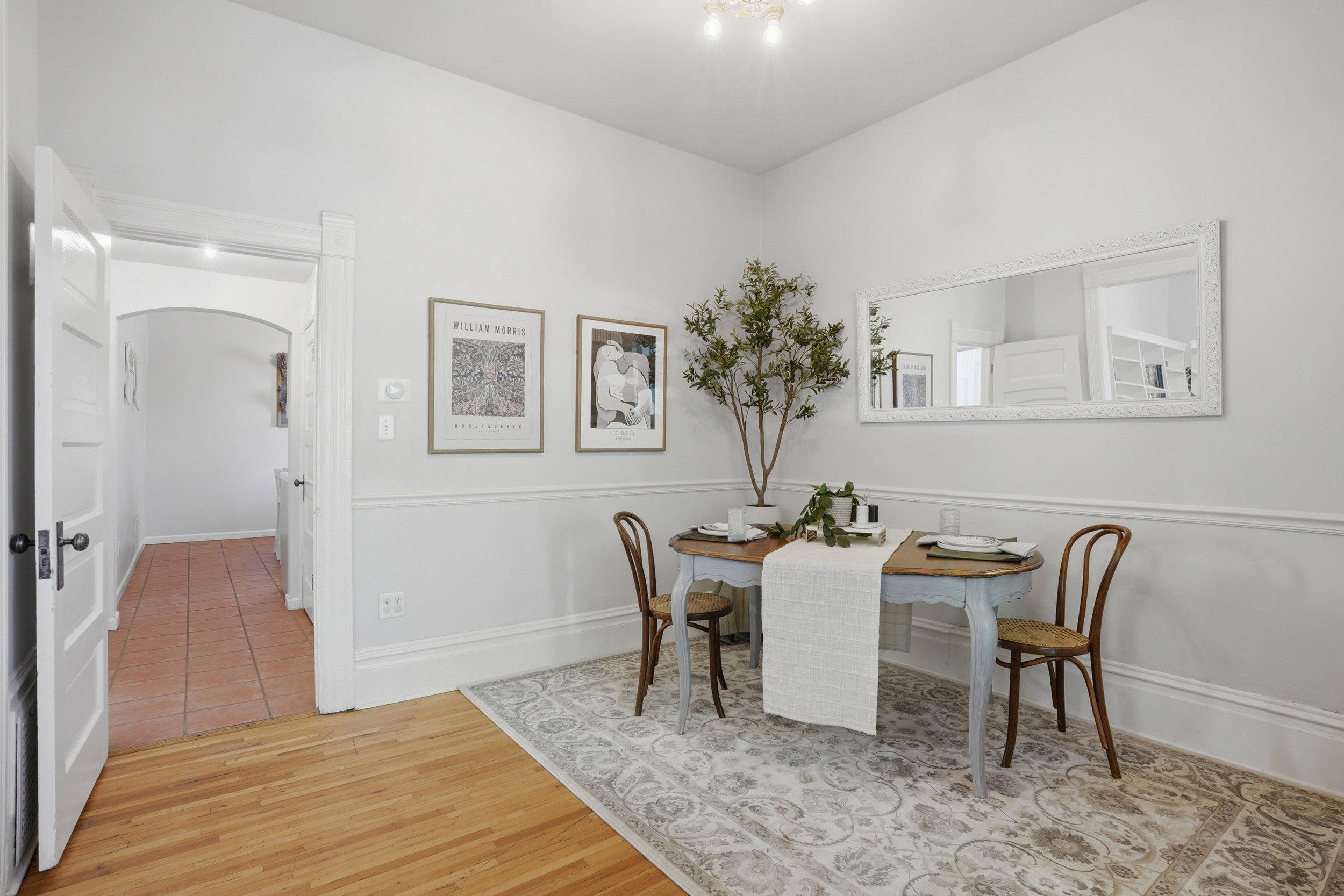 Formal dining area featuring hardwood flooring, white chair rail molding, and a decorative wall mirror