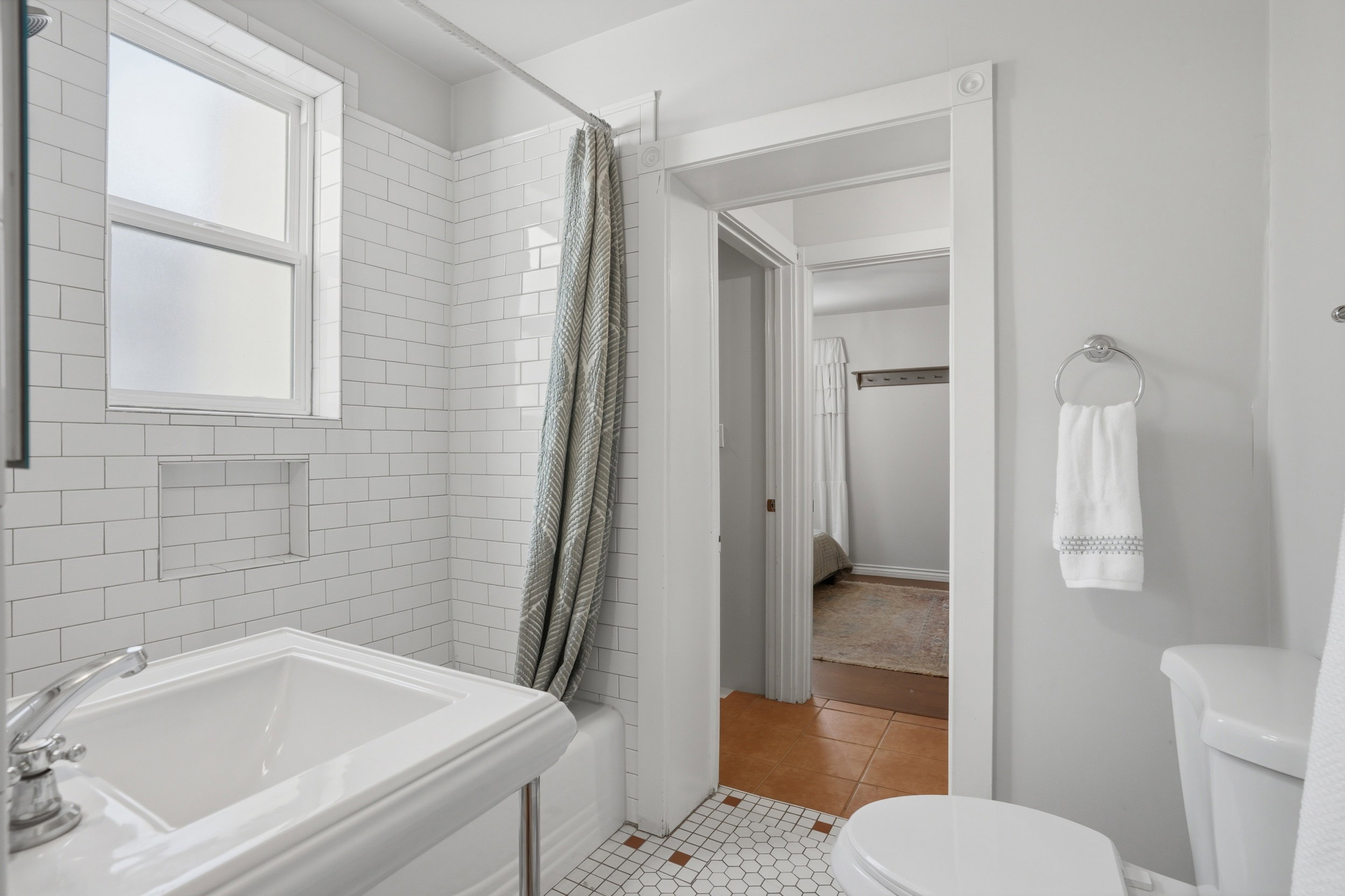 Bathroom featuring white subway tile surround, built-in shower niche, and hex tile flooring