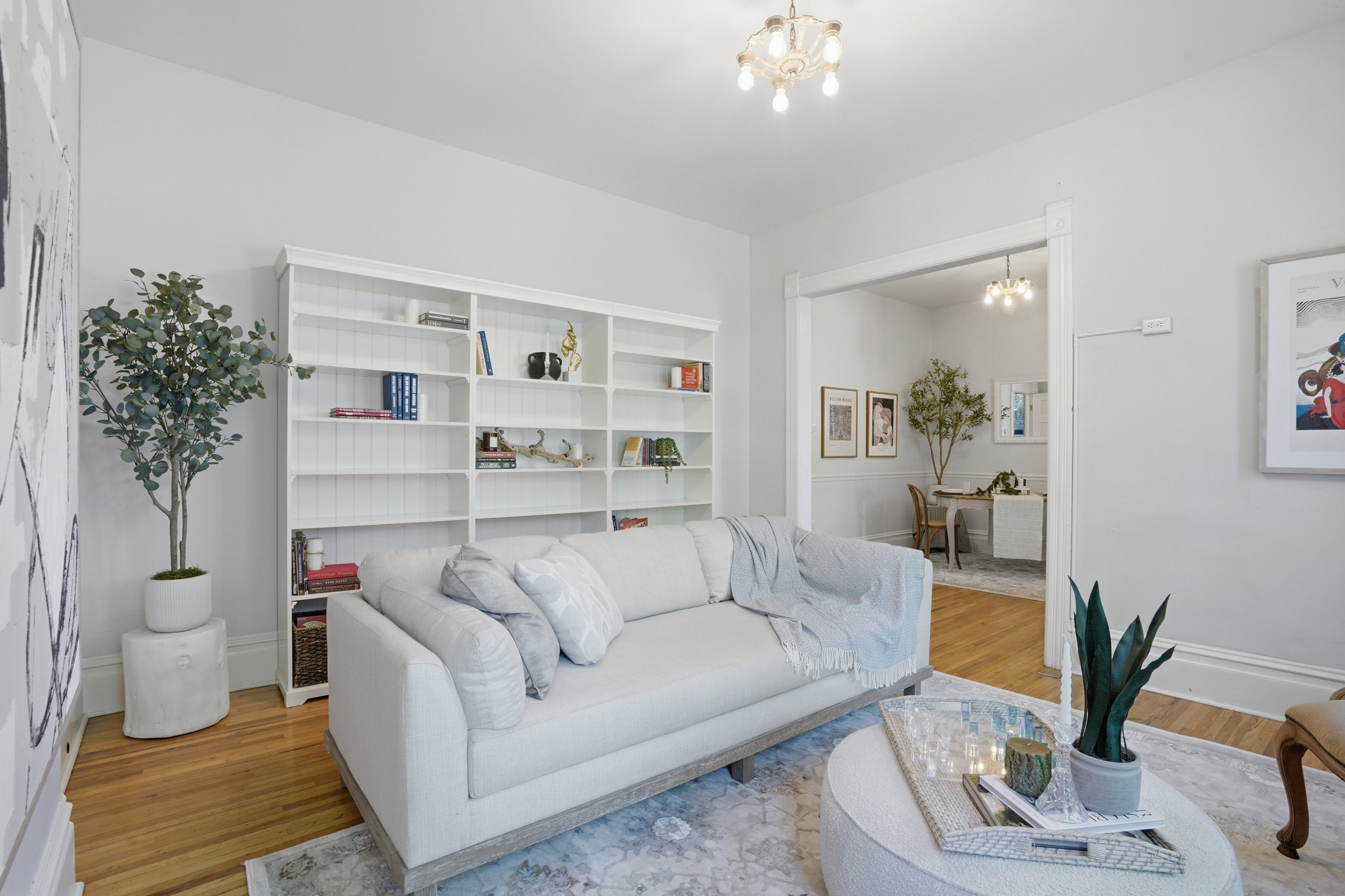 Living area featuring a full-wall built-in bookcase, polished wood-finish flooring, and a decorative ceiling light fixture