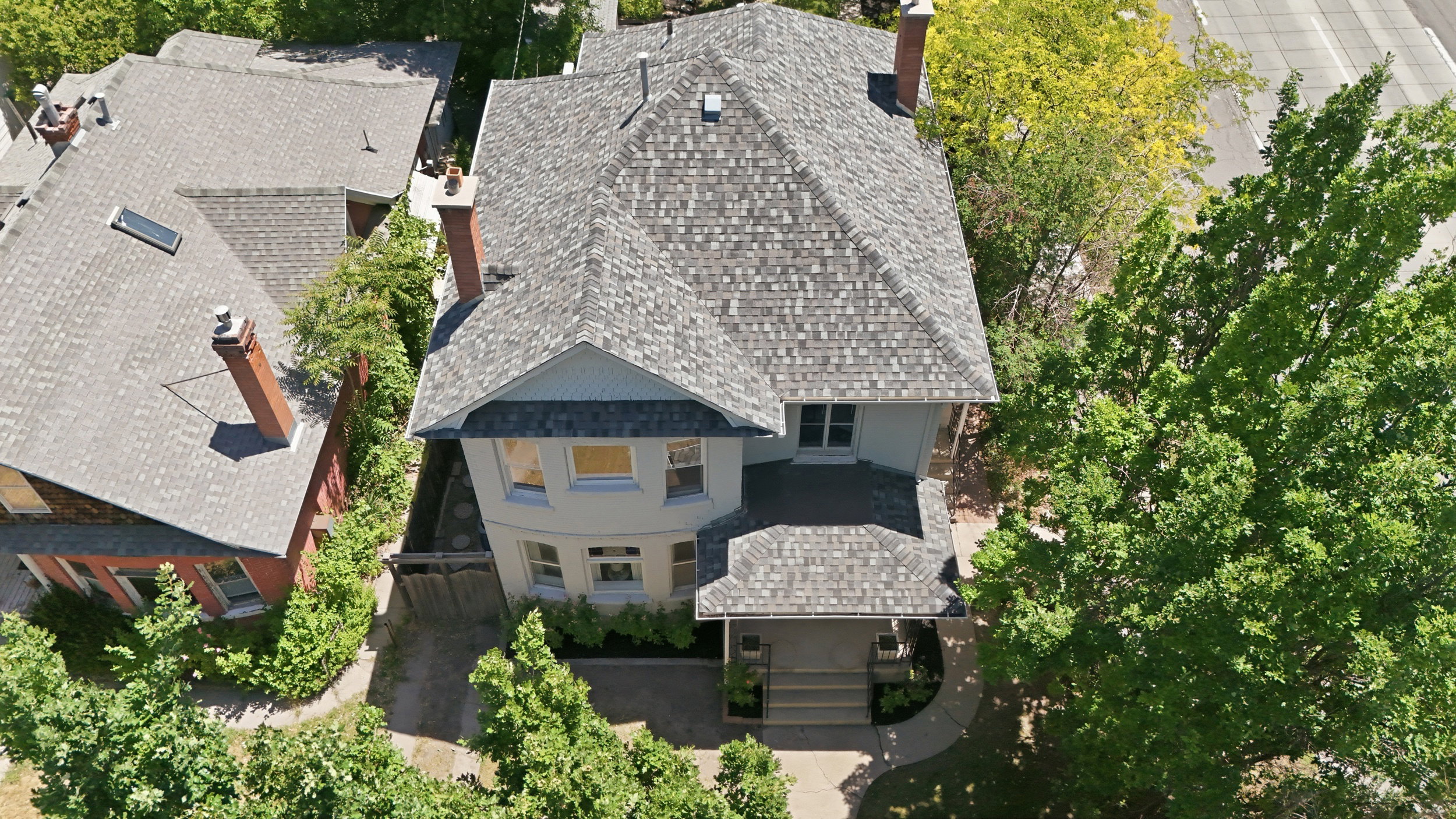 Traditional-style residence featuring a multi-gabled roof with grey shingles, an inviting covered front porch, and a bay window