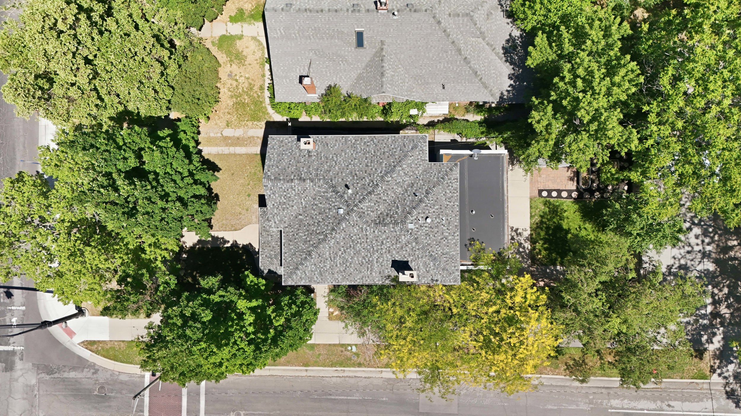 Aerial perspective showcasing a property with a grey shingled roof and a flat black roof section