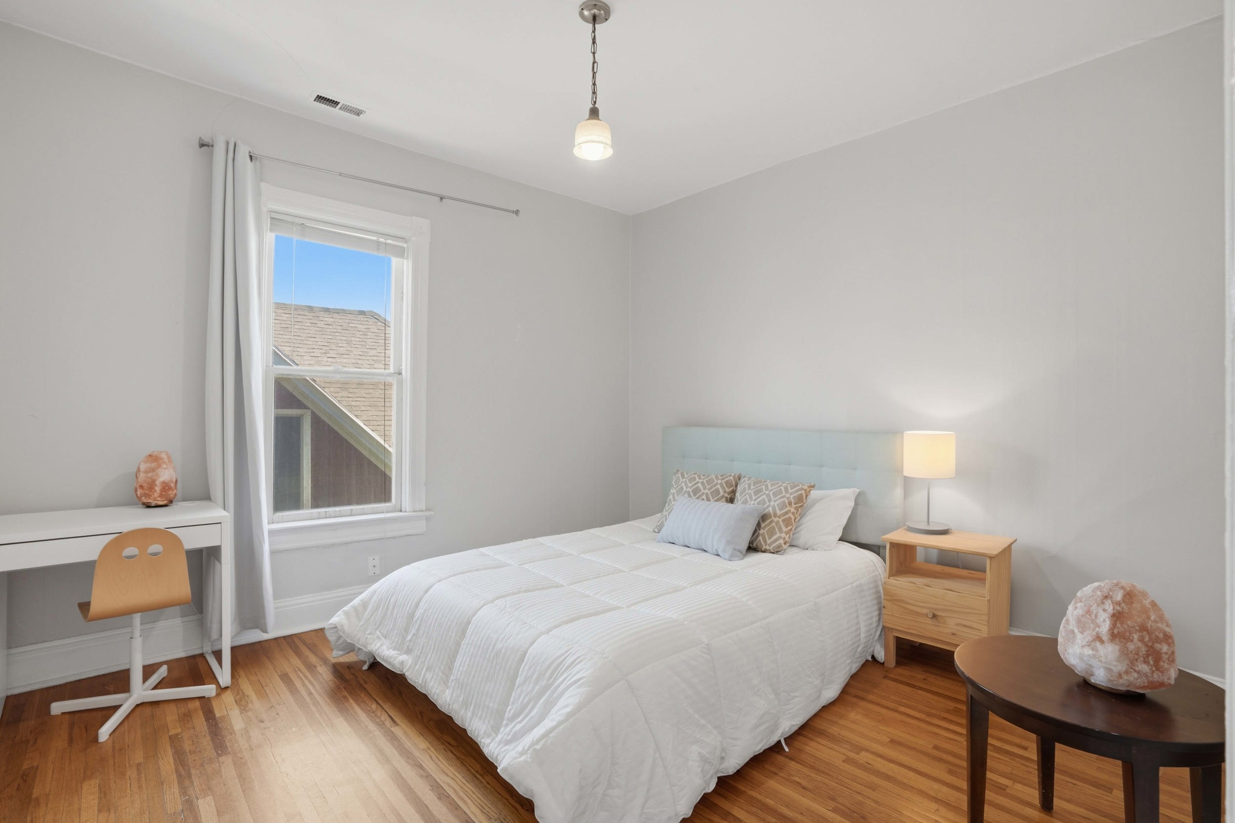 Room featuring wood-finish flooring, a double-hung window with white trim, and light gray wall paint