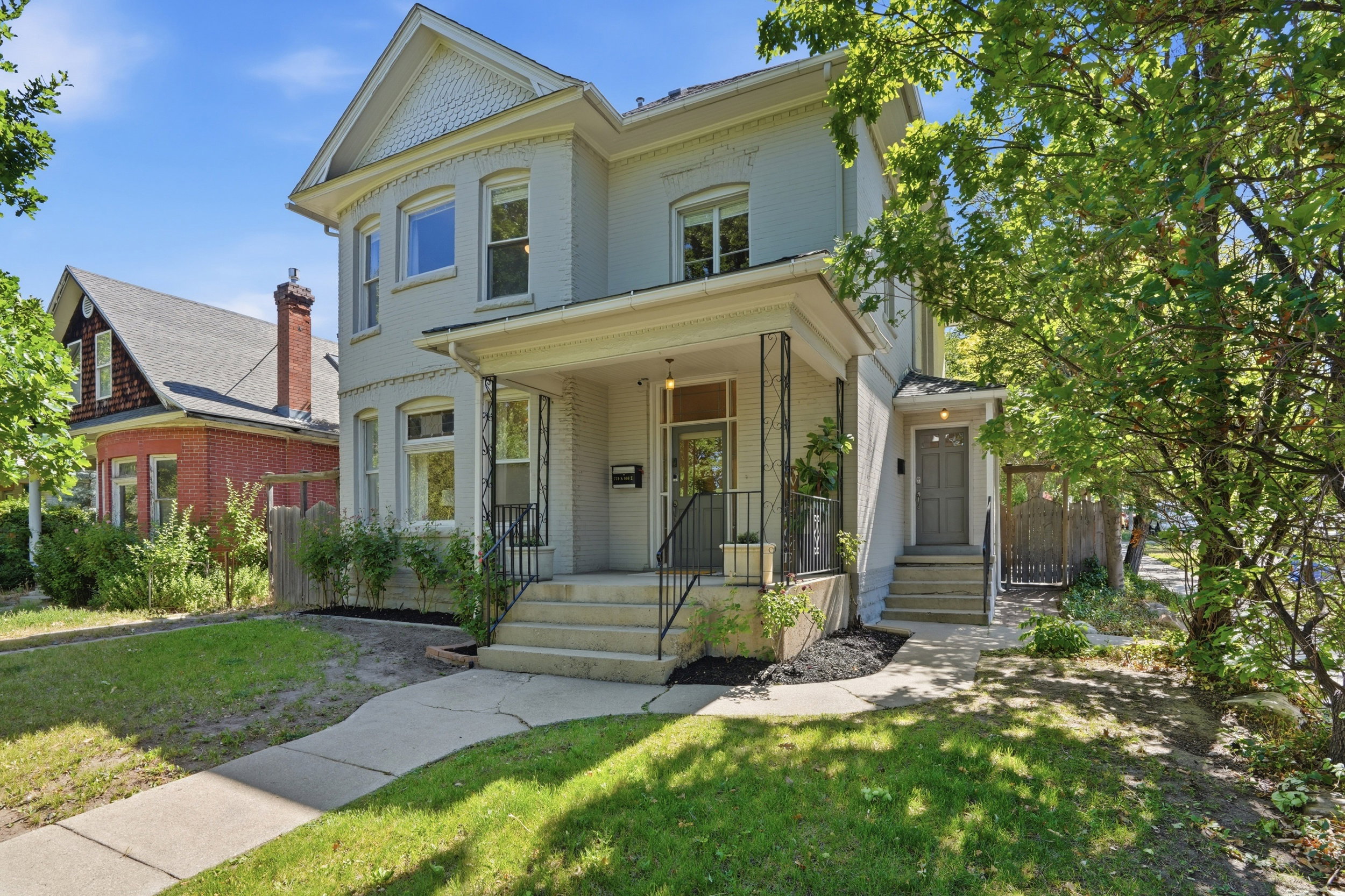 Classic two-story residence featuring a front porch with decorative ironwork, multiple windows with curved architectural details, and a distinctive gable roofline