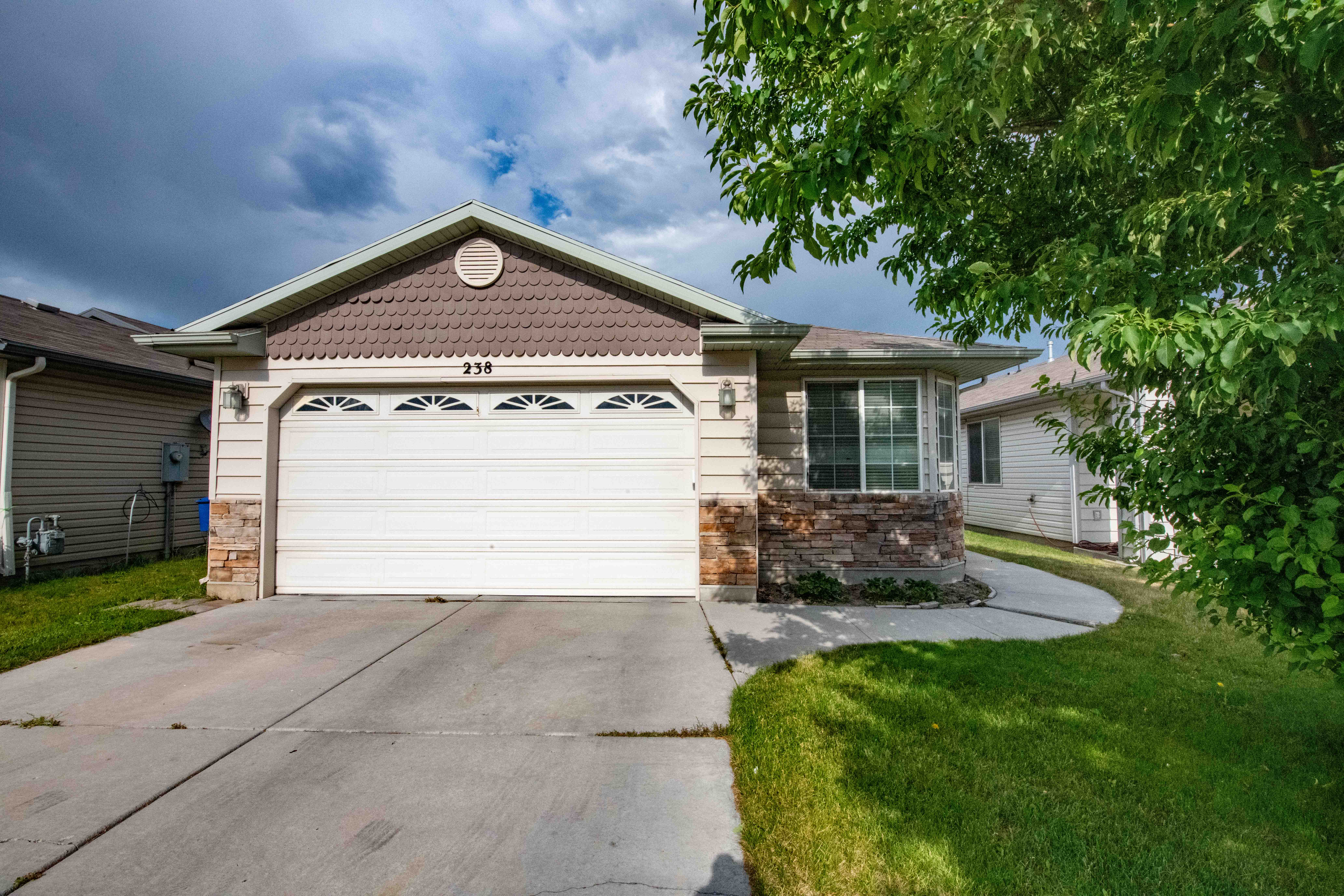 View of front of home featuring an attached garage, driveway, and stone siding