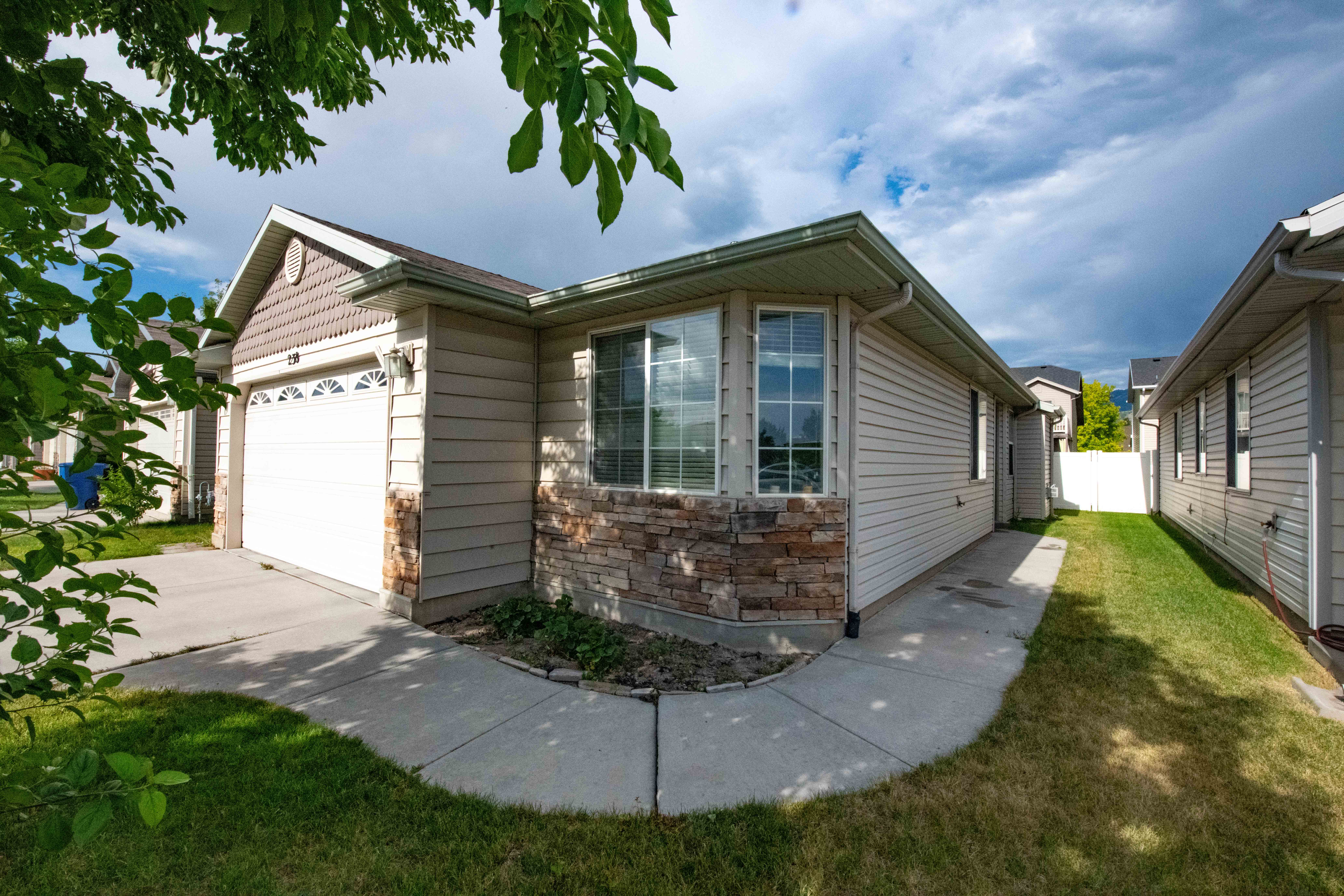 View of front of home featuring an attached garage, driveway, and stone siding